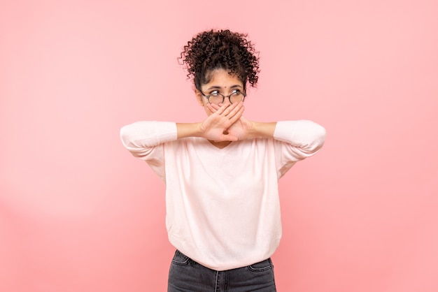 Free photo front view of young woman covering her mouth on pink wall