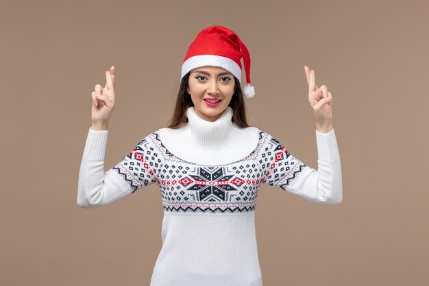 Front view young woman crossing her fingers on brown space