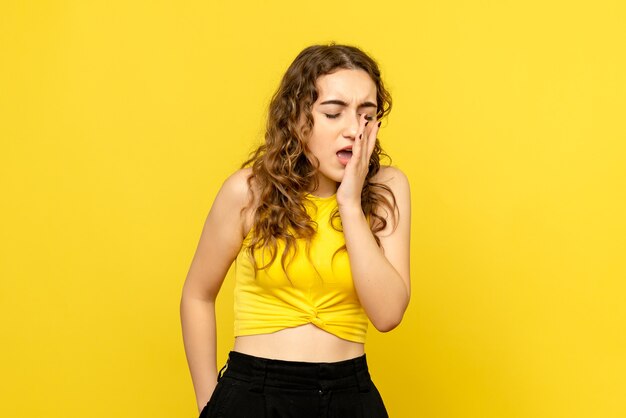 黄色の壁で泣いている若い女性の正面図