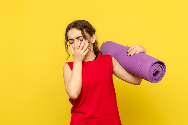 Vista frontale della giovane donna che piange sulla parete gialla