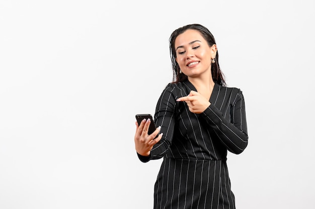 Front view young woman in dark strict suit holding phone on white background woman lady fashion office worker job beauty