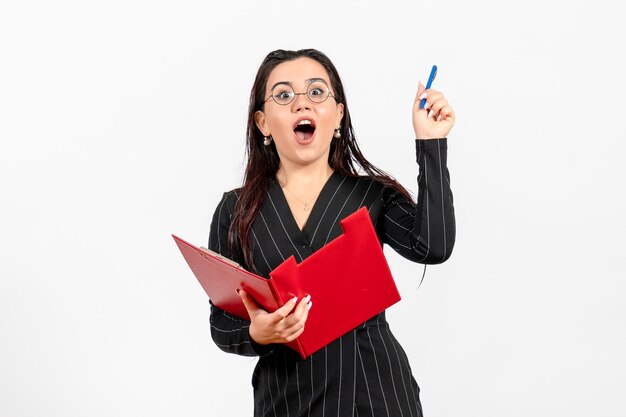 Front view young woman in dark strict suit holding red file on white background business female office document job