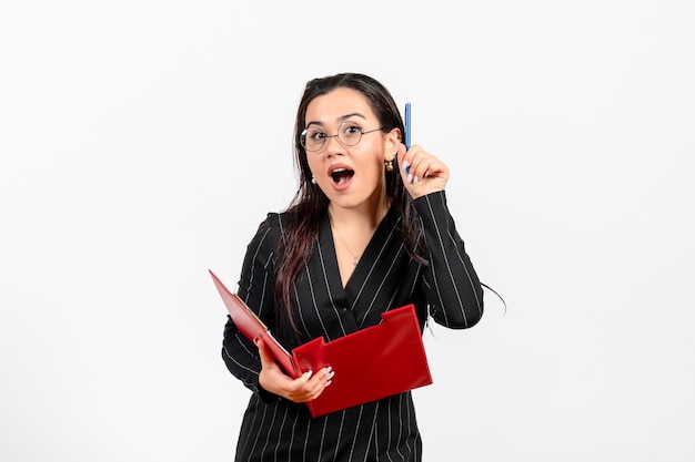 Front view young woman in dark strict suit holding red file with pen on white background office business job fashion female document