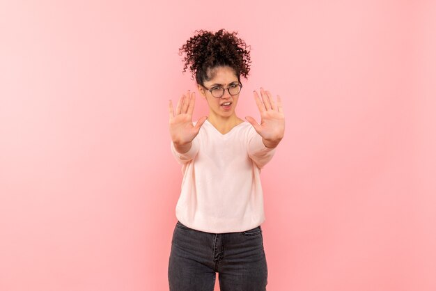 Front view of young woman displeased on pink wall