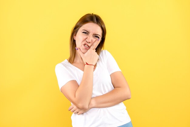 Front view of young woman displeased on yellow wall