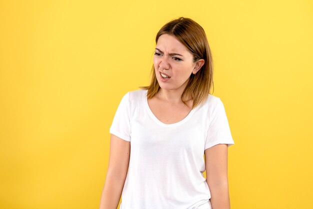 Front view of young woman displeased on yellow wall