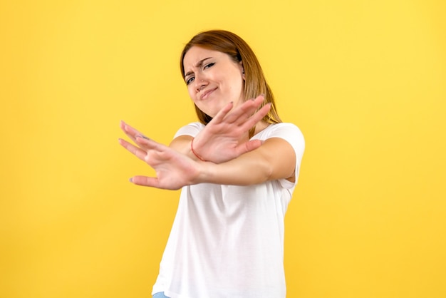 Front view of young woman displeased on yellow wall