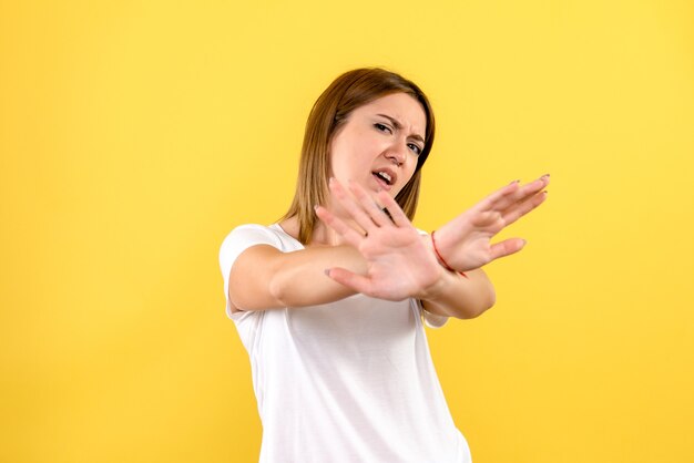 Front view of young woman displeased on yellow wall