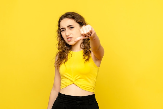 Вид спереди молодой женщины недоволен на желтой стене