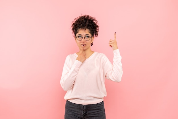 Front view of young woman dreaming on pink wall