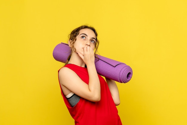 Front view of young woman dreaming on yellow wall