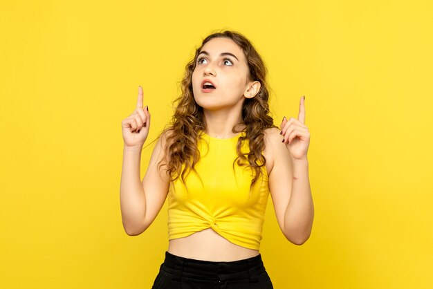 Front view of young woman dreaming on yellow wall