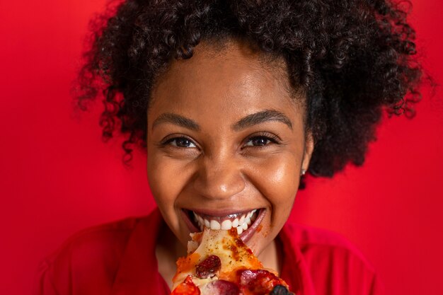 おいしいピザを食べる若い女性の正面図