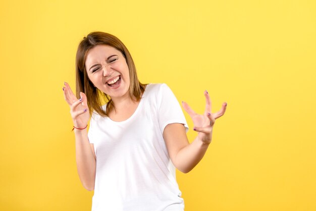 Front view of young woman excited on yellow wall