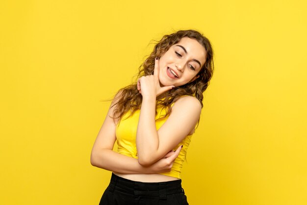 Front view of young woman excited on yellow wall