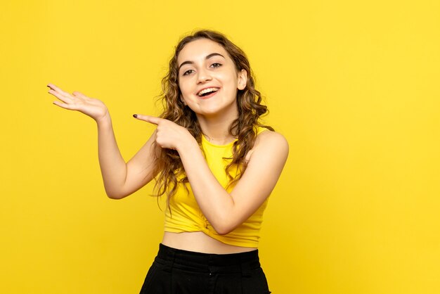 Front view of young woman excited on yellow wall