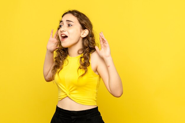 Вид спереди возбужденной молодой женщины на желтой стене