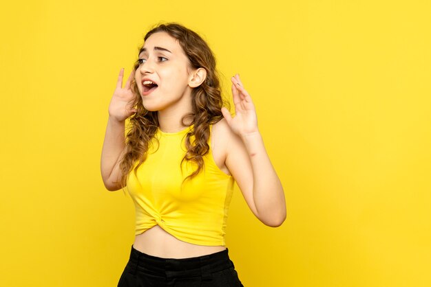 Front view of young woman excited on yellow wall