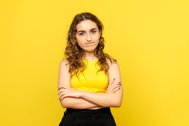 Front view of young woman feeling displeased on yellow wall