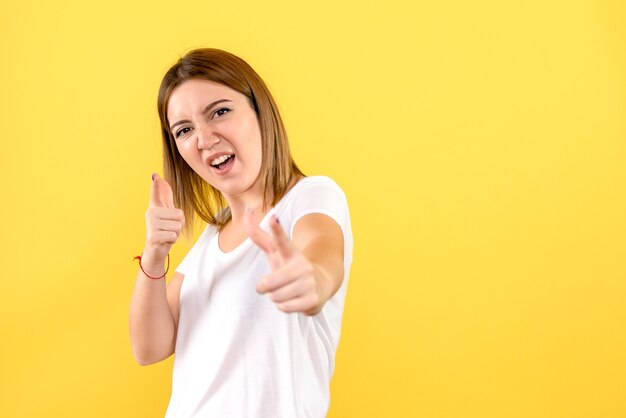 Front view of young woman feeling excited on yellow wall