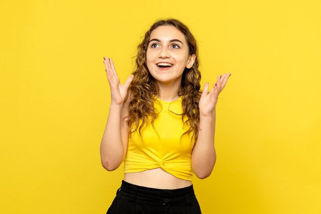 Free photo front view of young woman feeling excited on yellow wall