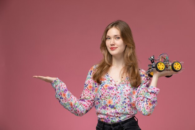 Вид спереди молодая женщина, дающая пустую руку с игрушкой автомобиля