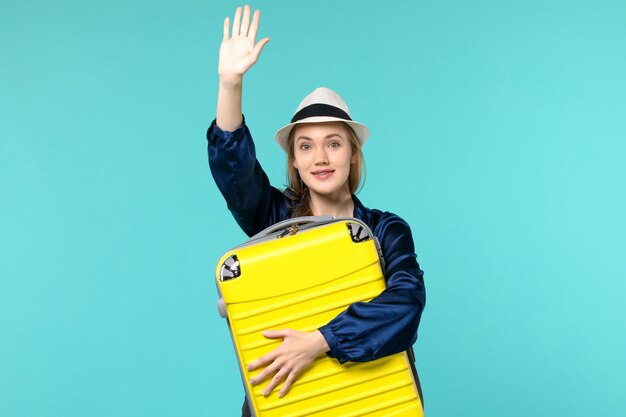 Front view young woman going in vacation and holding big bag greeting someone on blue background travel journey vacation sea voyage plane