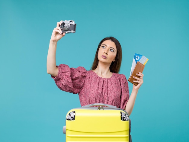 Front view young woman going in vacation holding camera and tickets on blue floor journey vacation woman sea abroad