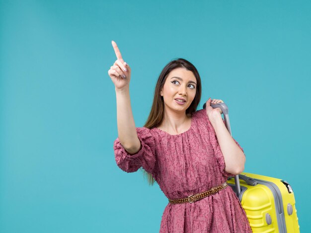 Front view young woman going in vacation with her yellow bag on a blue background journey summer trip woman human sea