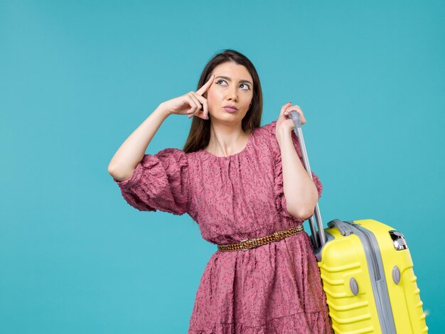 青い背景の旅夏の女性人間の旅の海に彼女の黄色いバッグと一緒に休暇に行く正面図若い女性