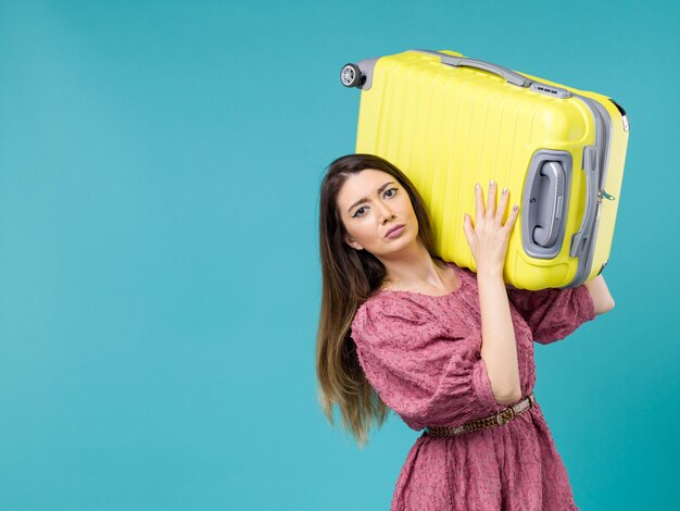 Front view young woman going in vacation with her yellow bag on a blue background summer journey human trip woman sea