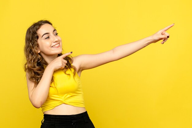 Front view of young woman happily smiling on yellow wall