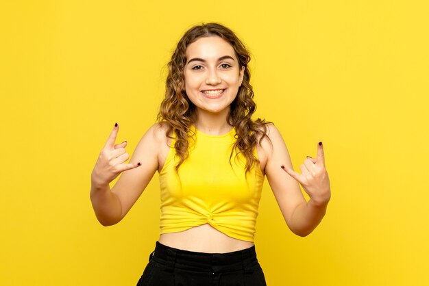 Front view of young woman happily smiling on yellow wall