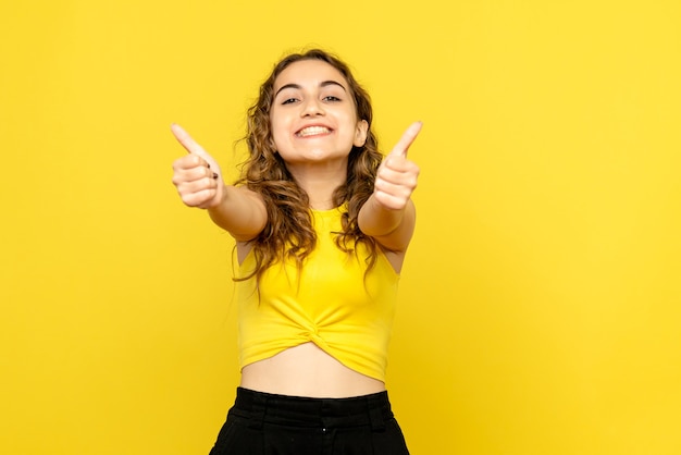 黄色い壁に幸せそうに笑っている若い女性の正面図