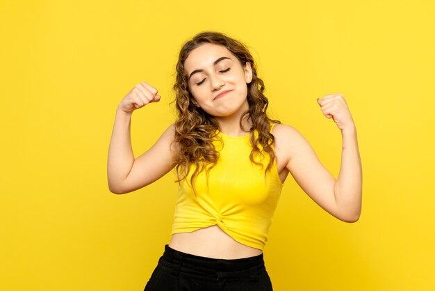 Front view of young woman happily smiling on yellow wall