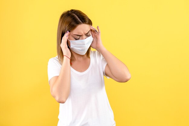 Front view of young woman having headache on yellow wall