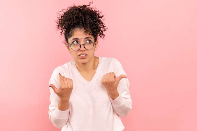 Front view of young woman hesitating on pink wall