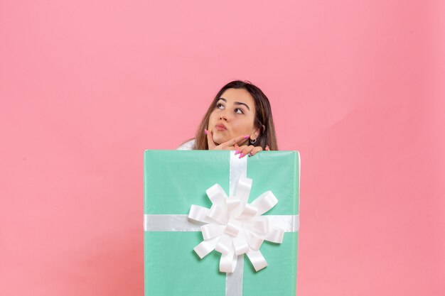 Front view young woman hiding inside present on a pink background