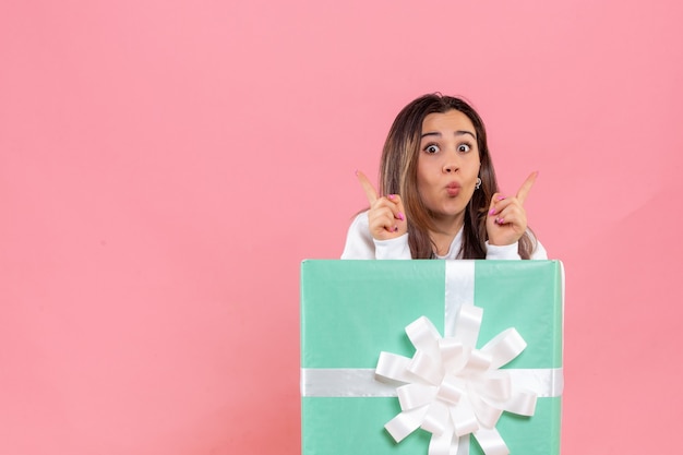 Front view young woman hiding inside present on a pink background