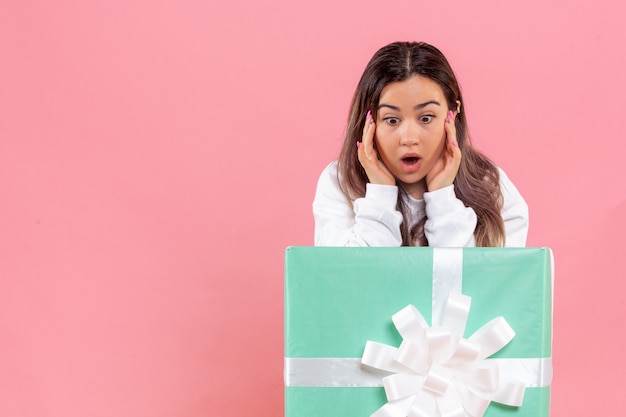 Free photo front view young woman hiding inside present on pink background