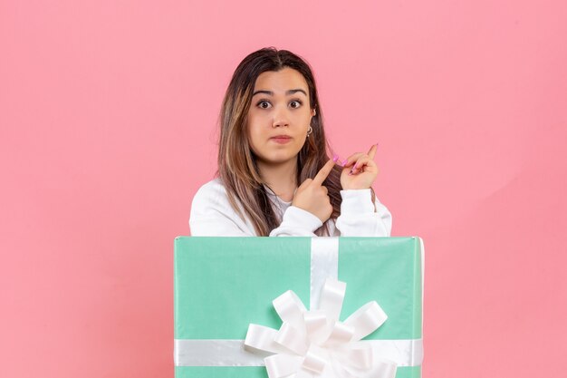 Front view young woman hiding inside present on pink background