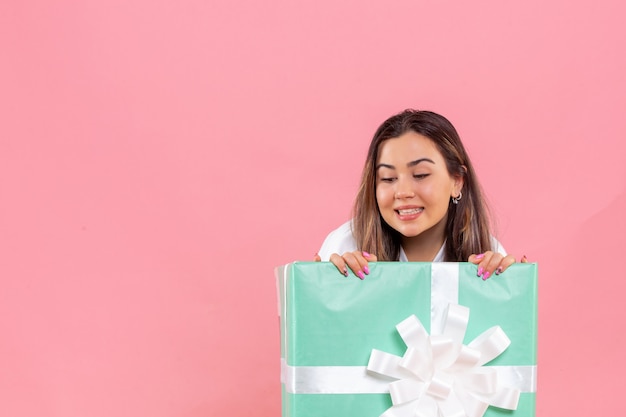 Front view young woman hiding inside present on pink background