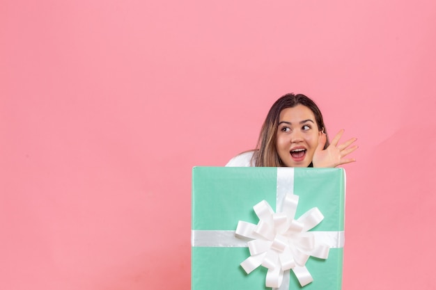 Free photo front view young woman hiding inside present on pink background