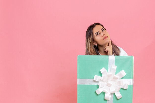 Front view young woman hiding inside present on the pink background