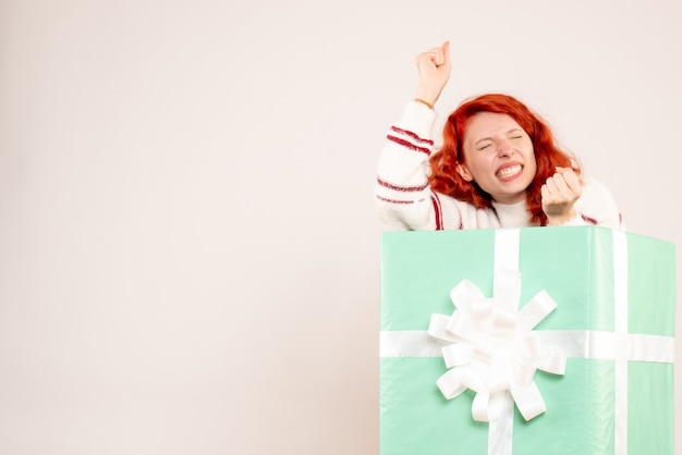 Free photo front view of young woman hiding inside present on a white wall