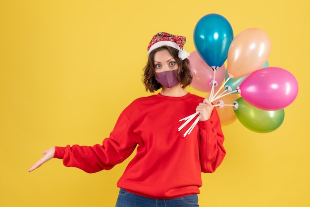 Front view young woman holding balloons on yellow