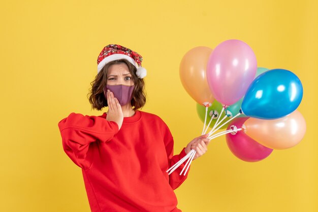 Front view young woman holding balloons on yellow