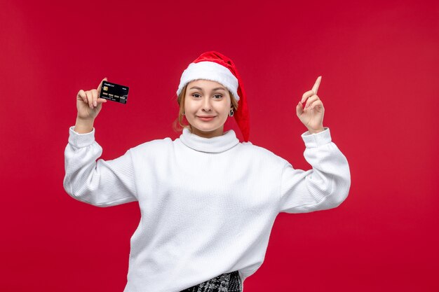 Front view young woman holding bank card on light red background