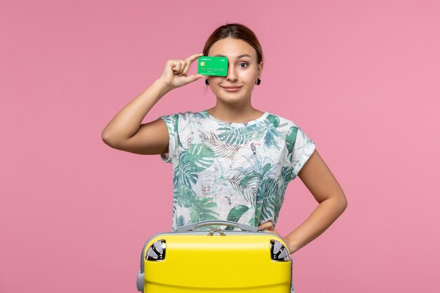 Бесплатное фото Вид спереди молодая женщина, держащая банковскую карту в отпуске на светло-розовой стене, летнее путешествие, поездка, отдых, женщина, отдых