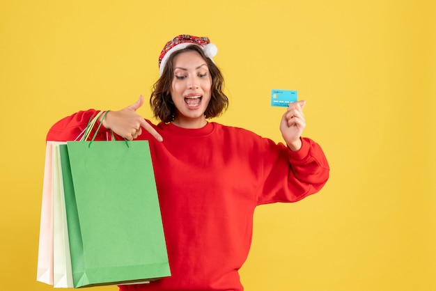 Front view young woman holding bank card and packages on the yellow